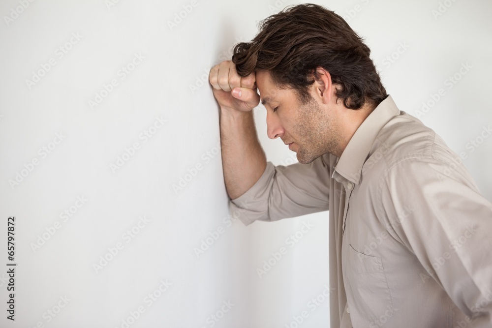 Casual worried businessman leaning head on wall Casual worried businessman leaning head on wall