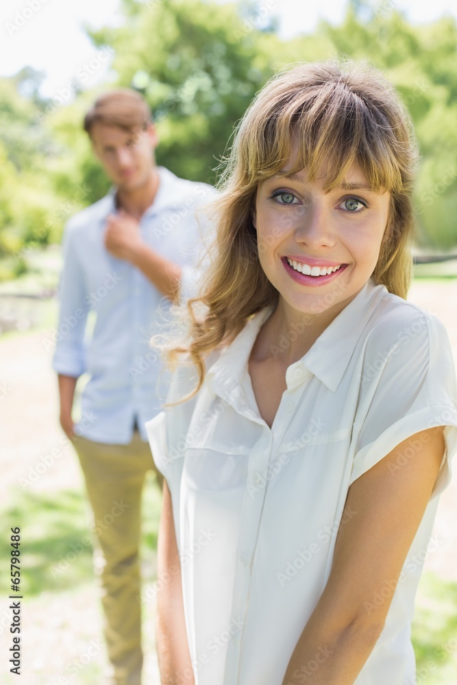 Beautiful blonde smiling at camera with boyfriend in background Beautiful blonde smiling at camera with boyfriend in background