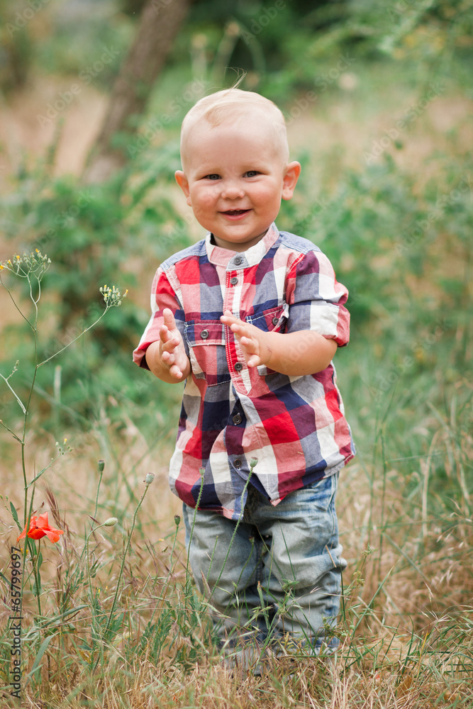 Fashion baby boy wearing checkered shirt walking in grass Fashion baby boy wearing checkered shirt walking in grass