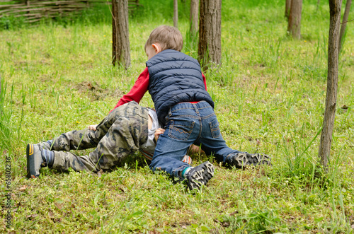 Two young boys fighting on the ground