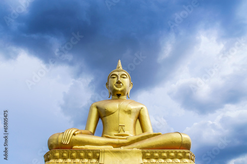 big  golden buddha statue sitting on blue sky background