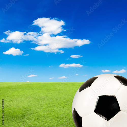 soccer ball with green grass field against blue sky