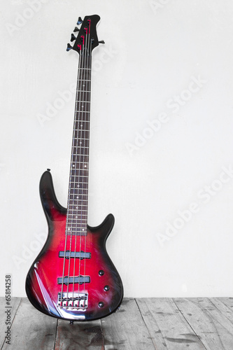 Red electric bass guitar leaning on wall and standing on table