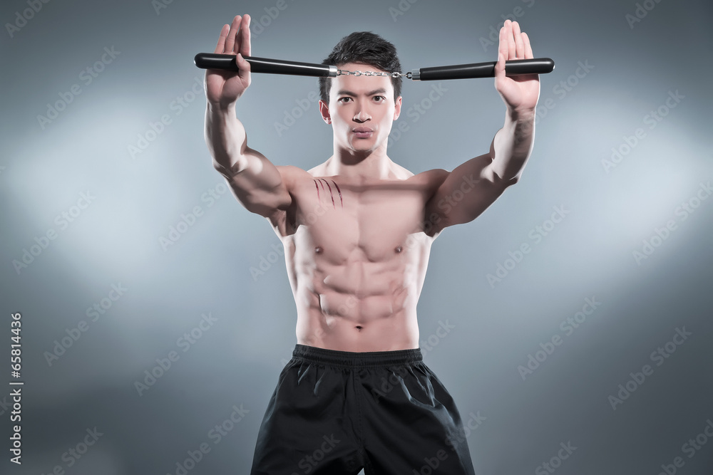 Muscled asian kung fu man in action pose with nunchucks. Blood s Muscled asian kung fu man in action pose with nunchucks. Blood s