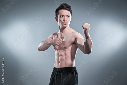 Fototapeta Muscled asian kung fu man in action pose. Blood stripes on his c