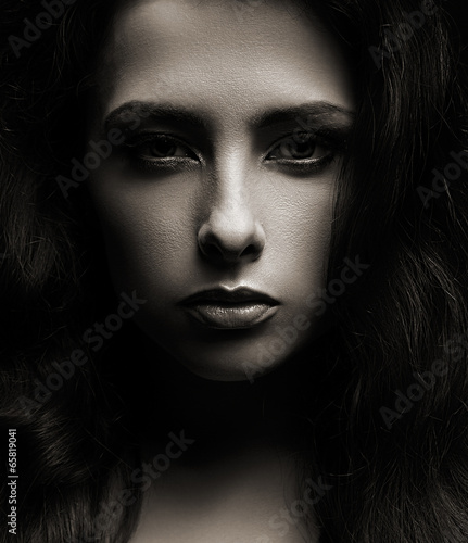 Closeup portrait of beautiful woman face on dark shadows