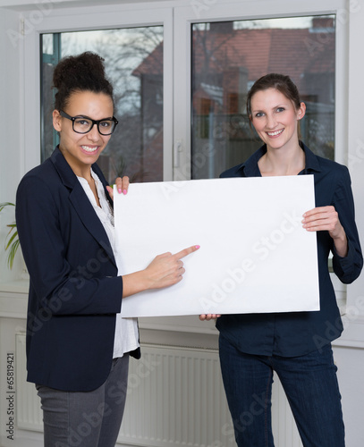 Zwei Frauen halten ein Plakat