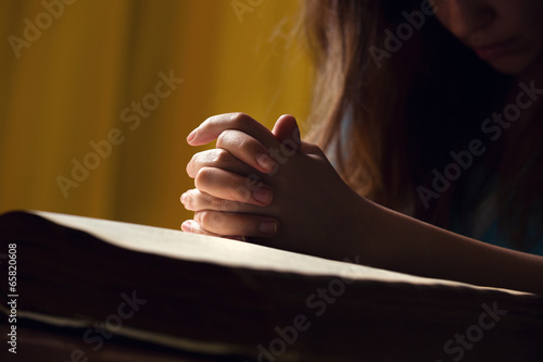 Girl Praying With Hands On Bible