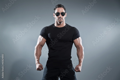 Obraz na płótnie Combat muscled action hero man wearing black t-shirt with pants w salonie