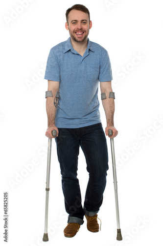 Fotografering Smiling young man using crutches