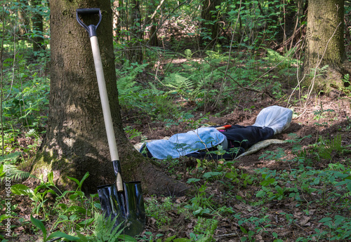 Shovel at the tree and man lying in the forest