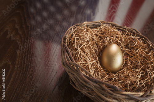 Fotografie Golden Egg in Nest with American Flag Reflection on Table