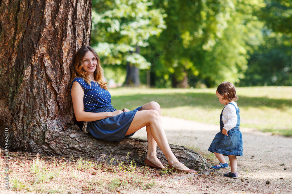 Happy young mother and adorable toddler girl walking through sum Happy young mother and adorable toddler girl walking through sum
