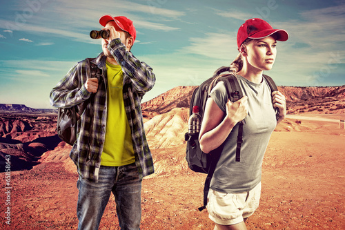 Young trekking couple with binocular in the desert.