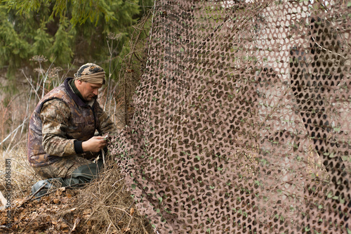 hunter places camouflage netting