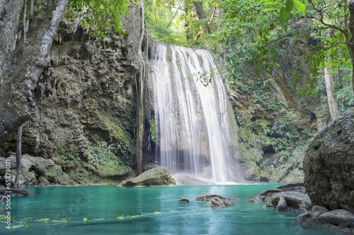 Waterfall, green forest in Erawan National Park, Thailand. Landscape with water flow, river, stream and rock at outdoor. Beautiful scenery of nature for tourist to tour, visit, relax in vacation.