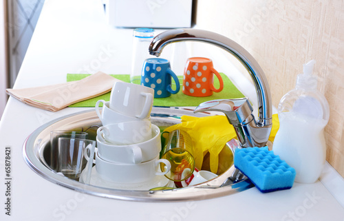 Stack of dishes soaking in kitchen sink