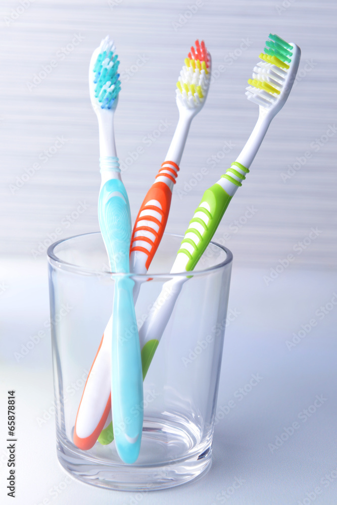 Toothbrushes in glass on table on light background Toothbrushes in glass on table on light background