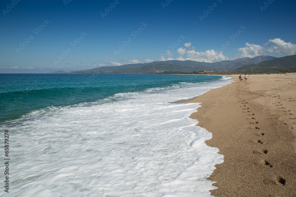 Obraz premium Two people walking along the beach at Sagone in Corsica