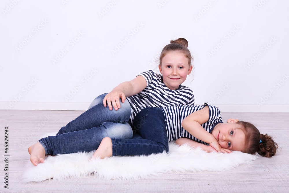 Beautiful small girls lying on floor on wall background Beautiful small girls lying on floor on wall background