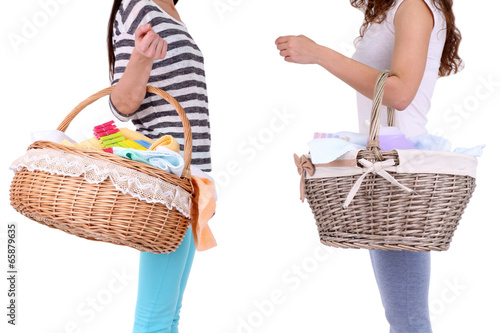 Women holding laundry baskets with clean clothes, towels and