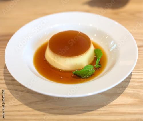 Delicious pudding with caramel and mint leaves. On a white backg