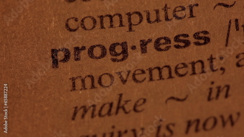 Word Progress in a dictionary. Lit with a spotlight. Three simil