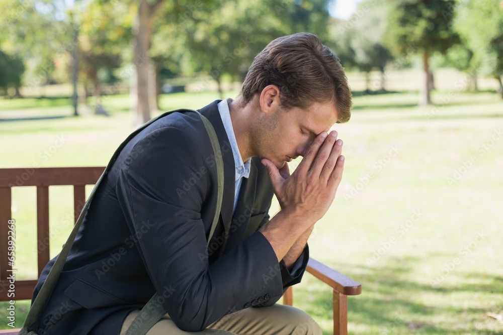Worried businessman sitting on park bench Worried businessman sitting on park bench
