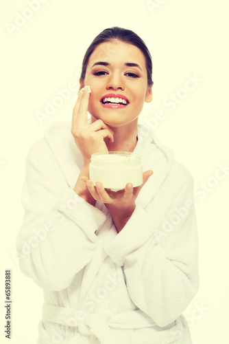 Beautiful woman in bathrobe with face cream
