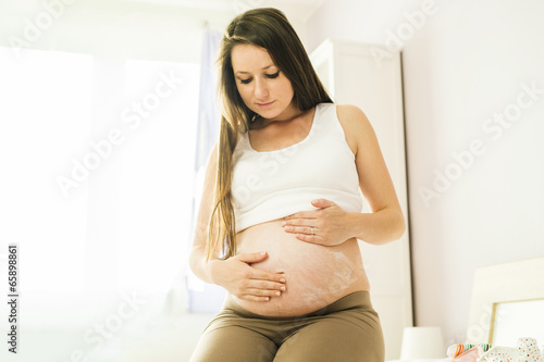 Pregnant woman appyling cream photo