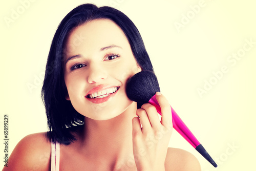 Attractive woman doing make-up on face.