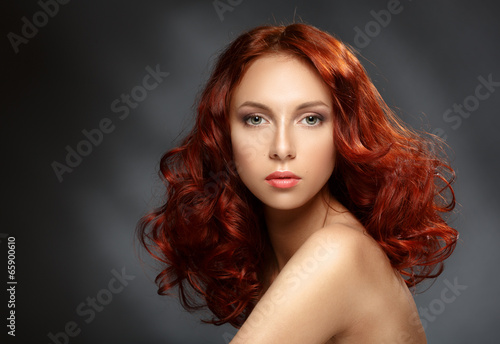 Portrait of a young ginger woman on a dark background.