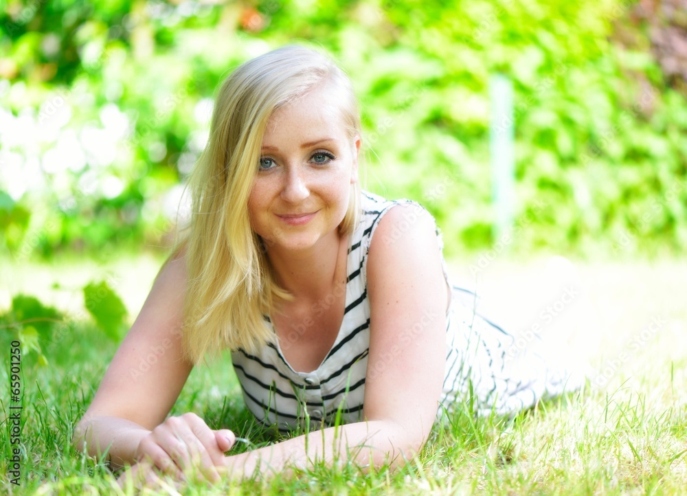 Young blonde woman woman laying on grass in park. Young blonde woman woman laying on grass in park.