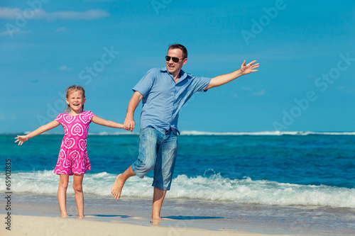 father and daughter standing on the beach in the day time