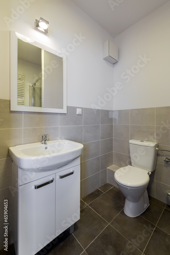 Modern tiled bathroom with toilet  sink and mirror