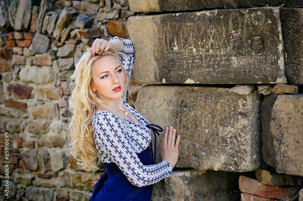 Sexy blond woman leaning against ancient stone wall Sexy blond woman leaning against ancient stone wall