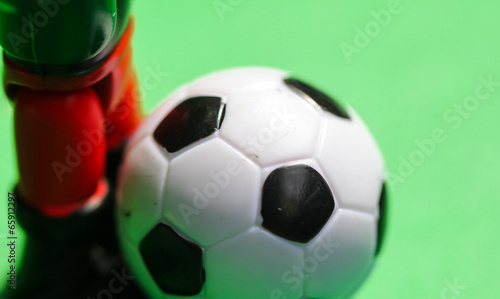 toy foot scores Gall by soccer ball on a green background