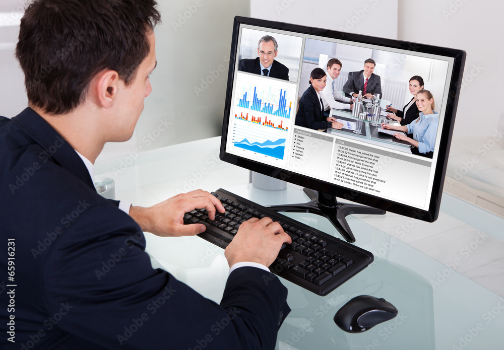 Businessman Video Conferencing With Team In Office Businessman Video Conferencing With Team In Office