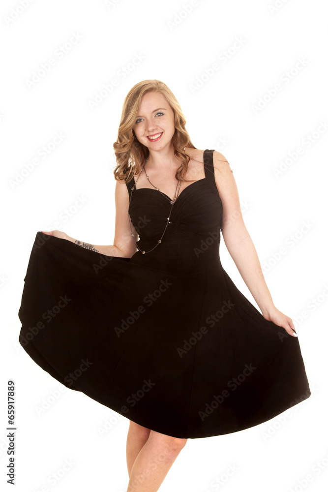 Naklejka premium woman hold out skirt of black dress smiling
