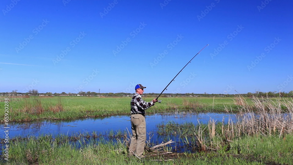 man fisherman catches fish on lake in bright day man fisherman catches fish on lake in bright day