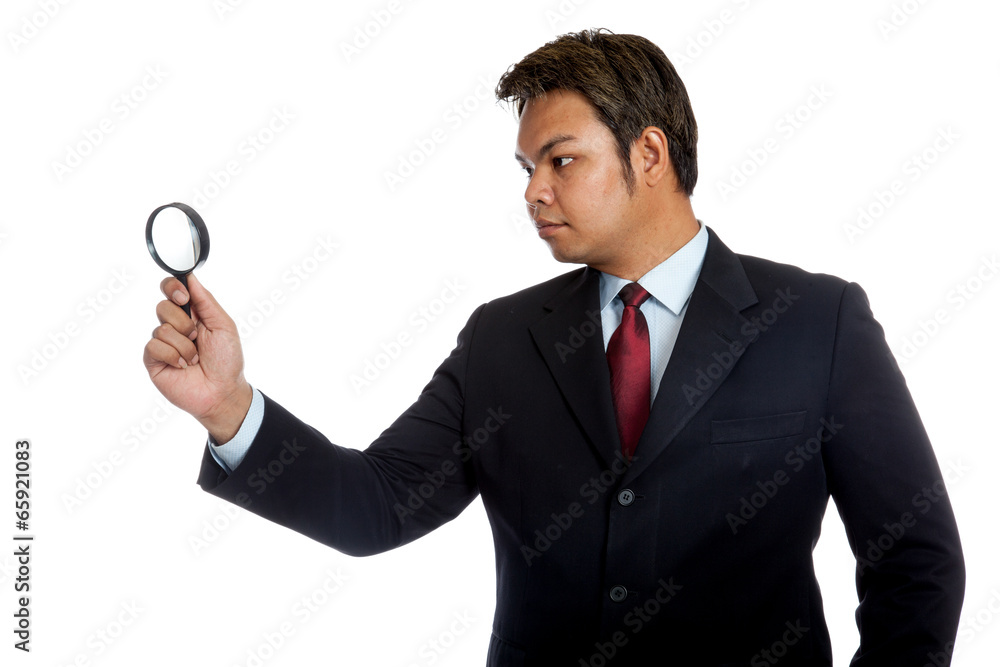 Asian businessman look through a magnifying glass Asian businessman look through a magnifying glass