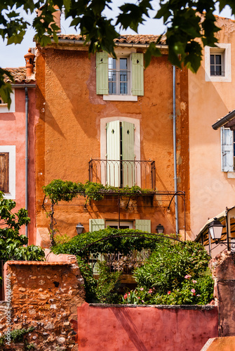Orange stone buildings with lush garden in France.