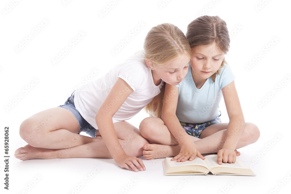 two young girls reading a book together