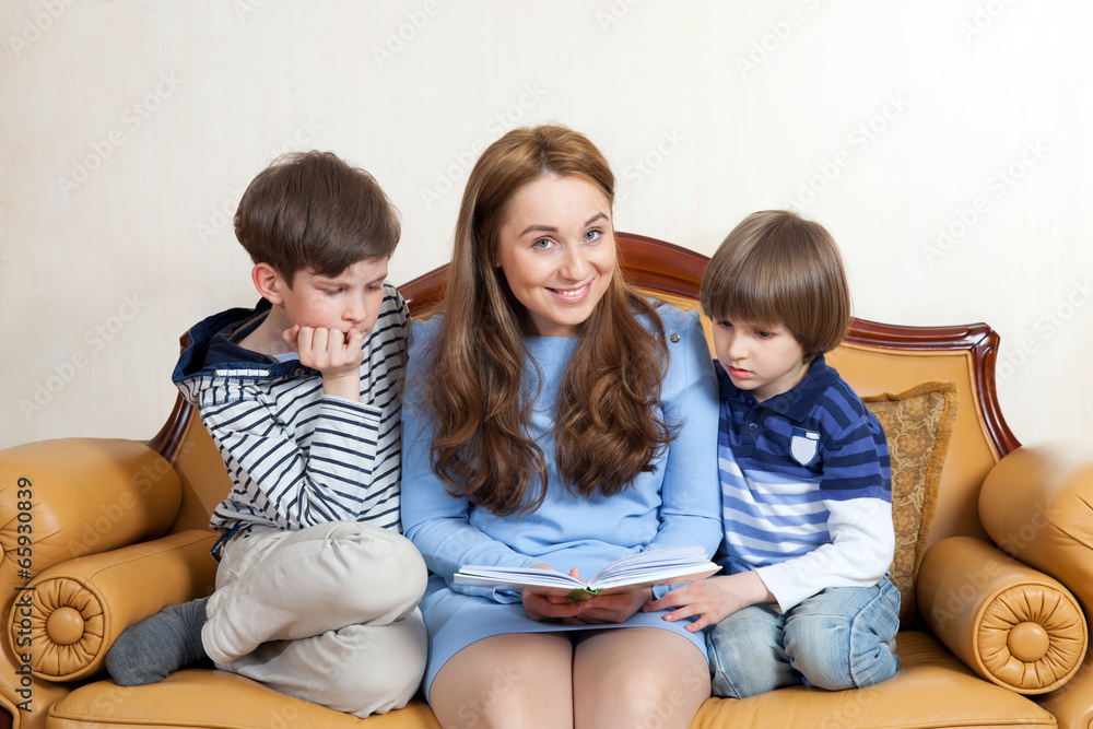 young woman with two children are reading a book young woman with two children are reading a book