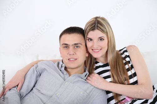 Loving couple sitting on sofa, on light background