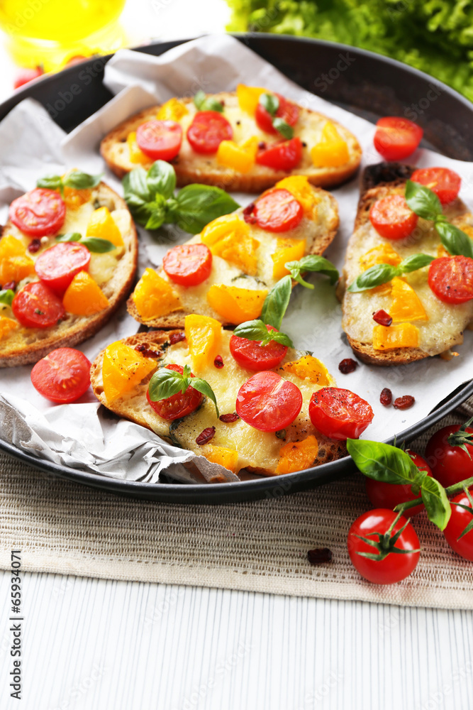 Tasty bruschetta with tomatoes in pan, on table Tasty bruschetta with tomatoes in pan, on table