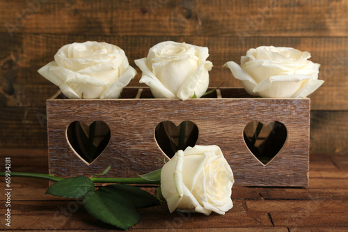Beautiful white roses in decorative box on wooden table