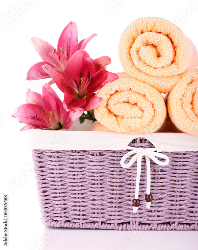 Fototapeta Naklejka Na Ścianę i Meble -  Color towels and lily flowers in wicket basket, isolated