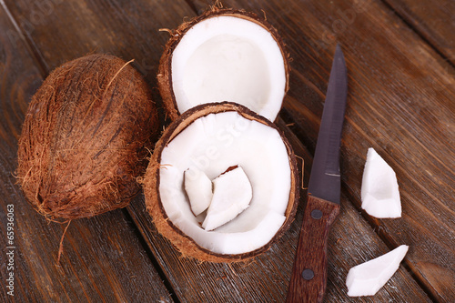 Broken coconut with knife on wooden background