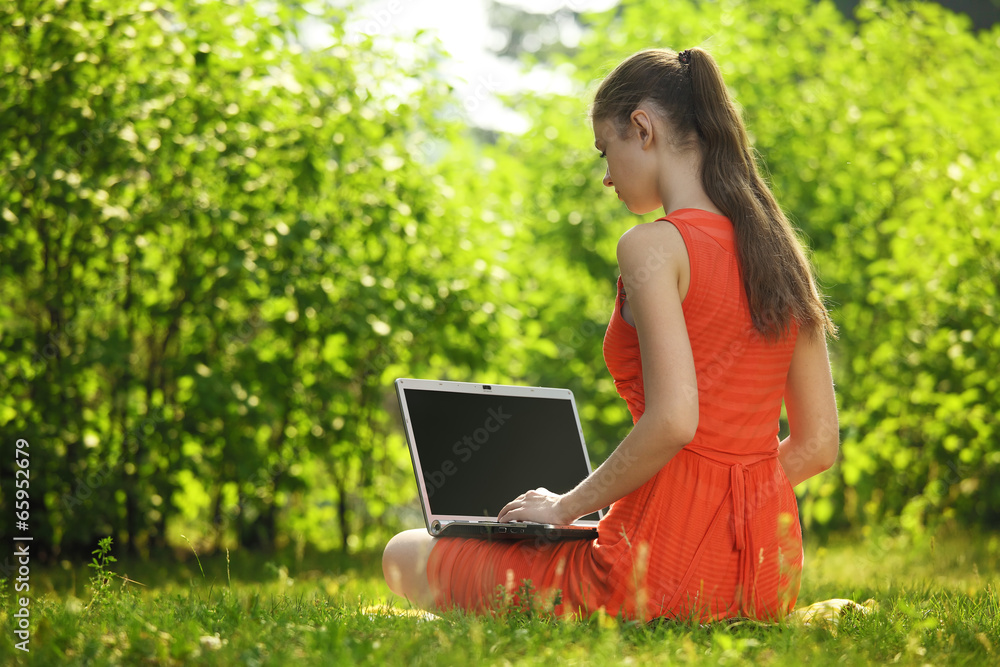 Young woman with laptop on green grass at park Young woman with laptop on green grass at park